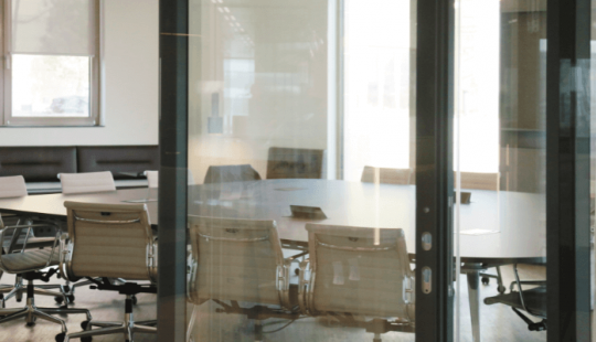 Moderne vergaderruimte met glazen wanden, ingebouwde verlichting en ergonomische stoelen.