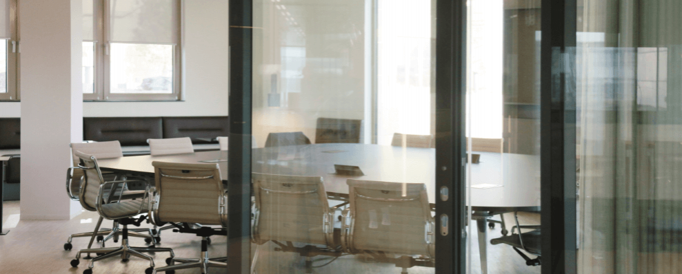 Moderne vergaderruimte met glazen wanden, ingebouwde verlichting en ergonomische stoelen.