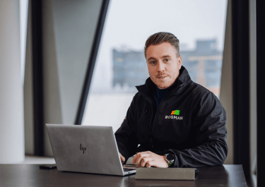 Een projectleider werktuigbouwkunde bij Bosman zit achter zijn laptop in een moderne kantooromgeving.