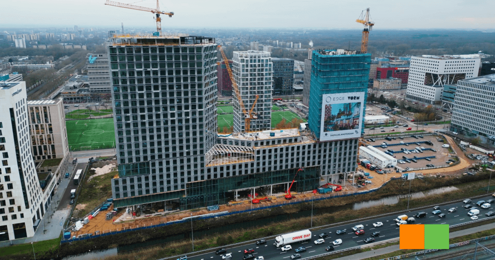 Luchtfoto van The Pulse of Amsterdam in aanbouw – een duurzaam mixed-use gebouw met woningen, kantoren en commerciële ruimtes aan de Zuidas.