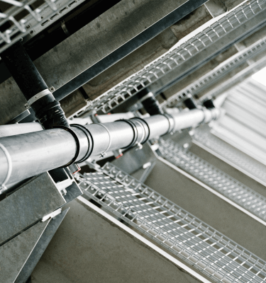 Gedetailleerd beeld van metalen leidingen in een gebouw, bevestigd aan een stalen constructie.