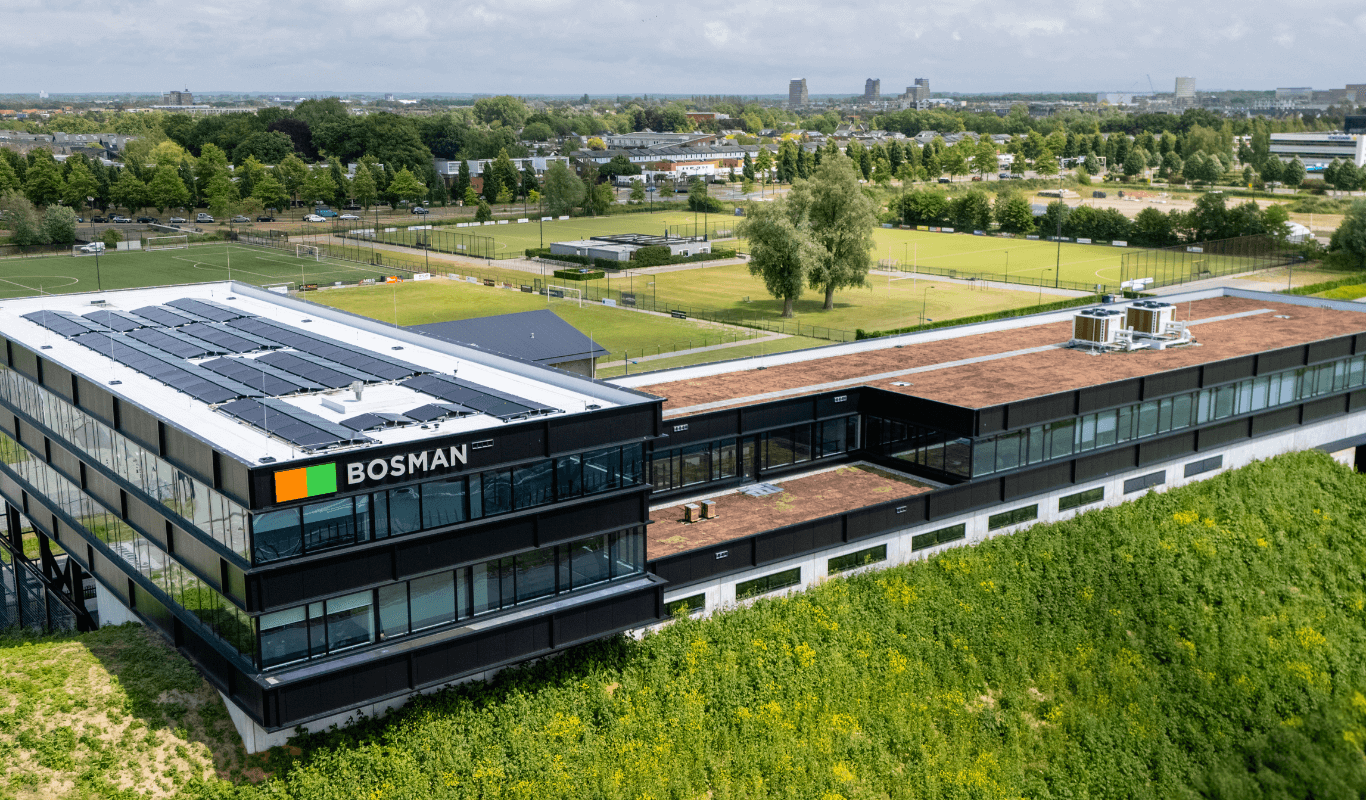 Achterzijde van het nieuwe Bosman-kantoor langs de A1 bij Amersfoort, met grote glaspartijen en uitzicht op de snelweg vanaf een verhoogde geluidswal.