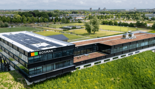 Achterzijde van het nieuwe Bosman-kantoor langs de A1 bij Amersfoort, met grote glaspartijen en uitzicht op de snelweg vanaf een verhoogde geluidswal.