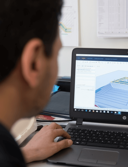 Medewerker van Bosman werkt aan een digitaal technisch model op een laptop, waarbij multidisciplinaire installaties worden ontworpen volgens de wensen en behoeften van de klant.