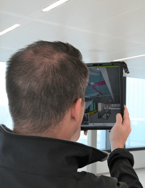 Man bekijkt een technisch ontwerp op een tablet bij een bouwproject.