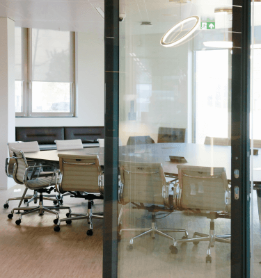 Moderne vergaderruimte met glazen wanden, ingebouwde verlichting en ergonomische stoelen.