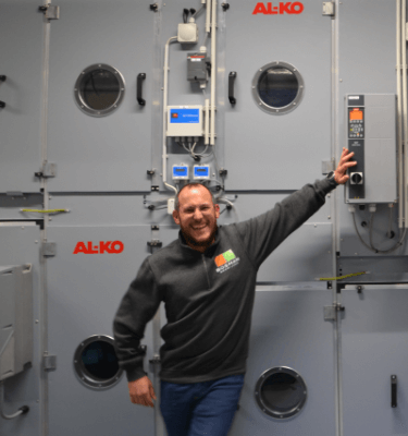 Een enthousiaste medewerker van Bosman poseert bij een technische installatie. Werken bij Bosman betekent een dynamische werkomgeving met innovatieve projecten.