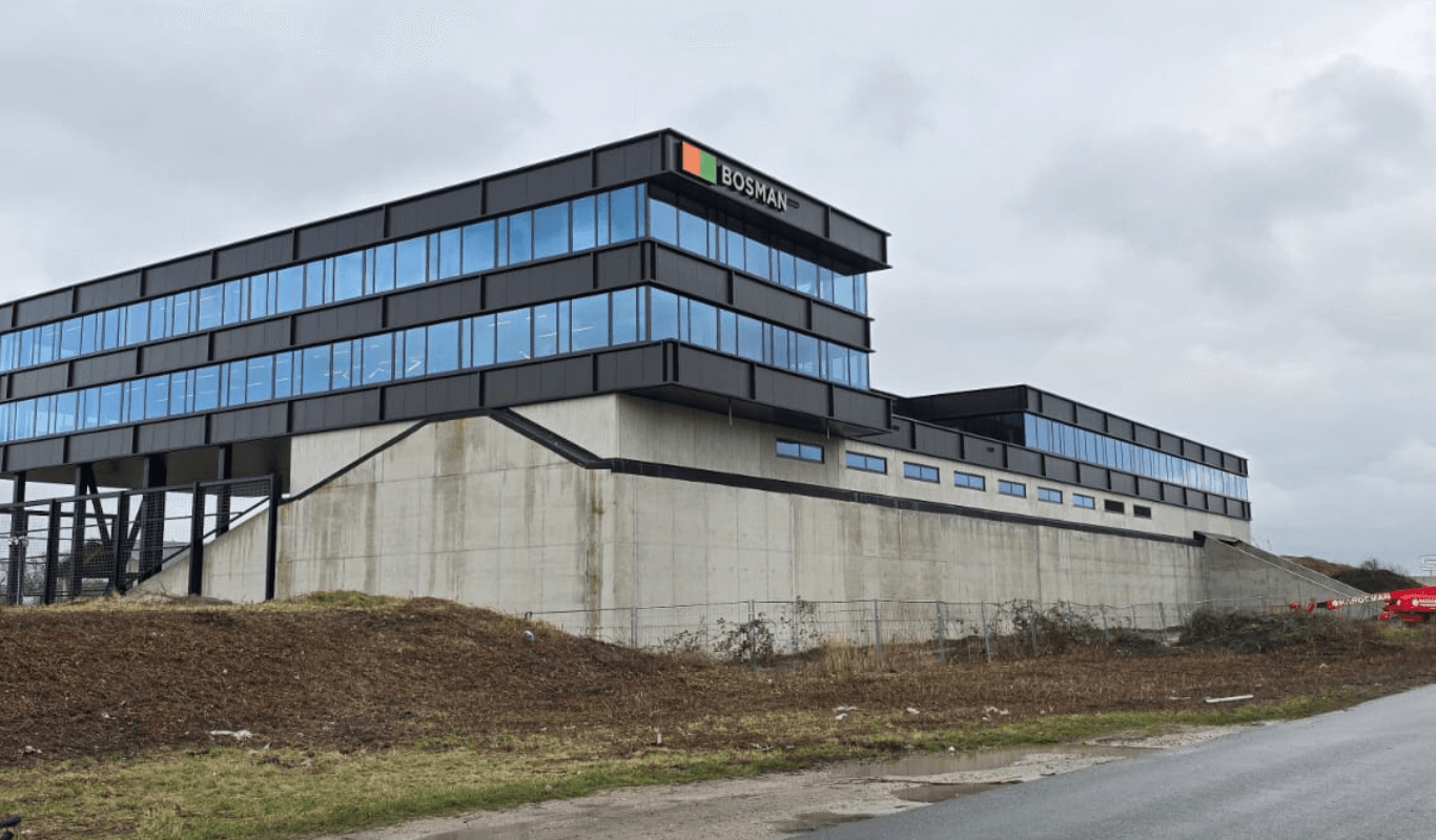 Achterzijde van het nieuwe Bosman-kantoor langs de A1 bij Amersfoort, met grote glaspartijen en uitzicht op de snelweg vanaf een verhoogde geluidswal.