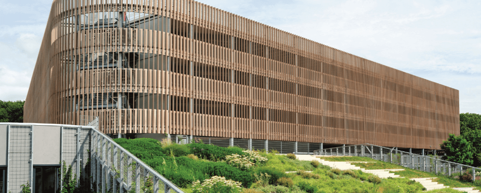 P+R Genneper Parken in Eindhoven, een duurzaam ontworpen parkeergarage met een houten gevel en groene daken, geïntegreerd in een natuurlijke omgeving.
