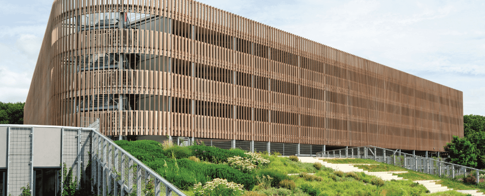 P+R Genneper Parken in Eindhoven, een duurzaam ontworpen parkeergarage met een houten gevel en groene daken, geïntegreerd in een natuurlijke omgeving.