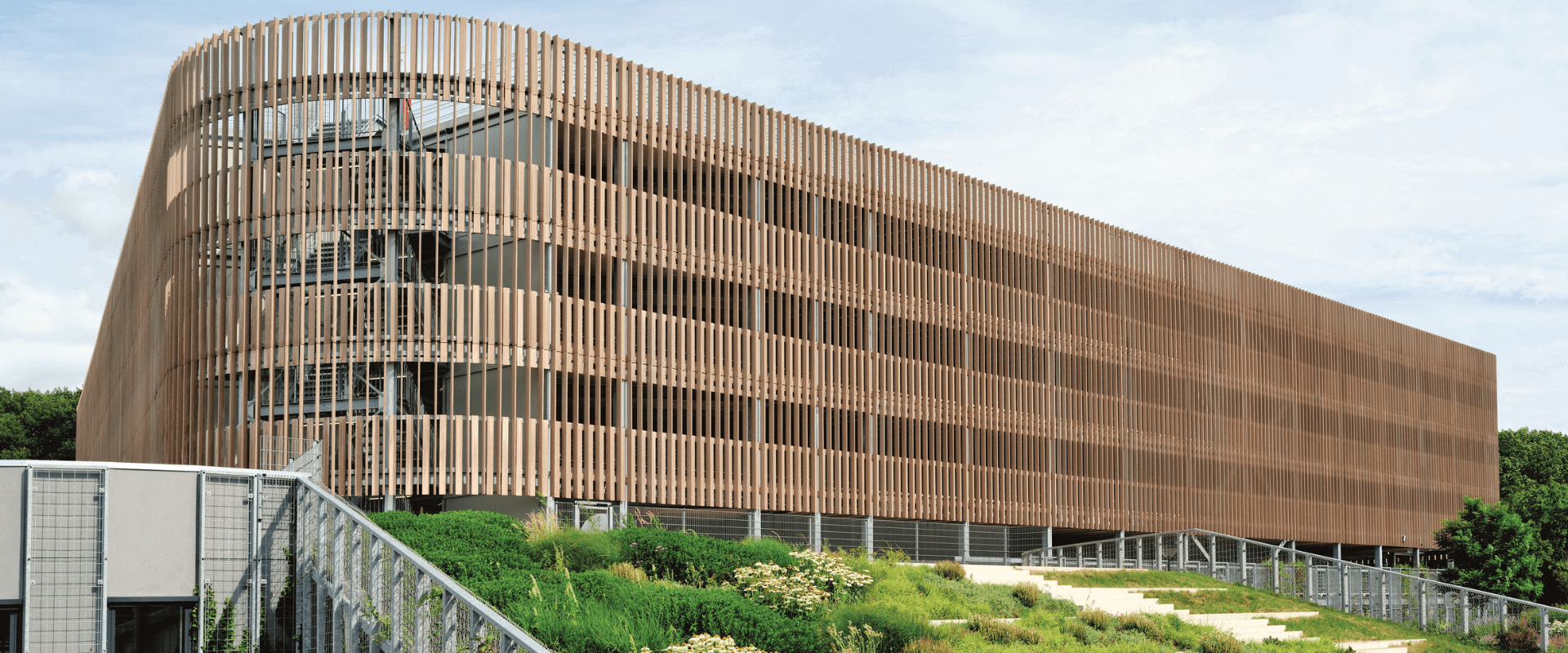 P+R Genneper Parken in Eindhoven, een duurzaam ontworpen parkeergarage met een houten gevel en groene daken, geïntegreerd in een natuurlijke omgeving.