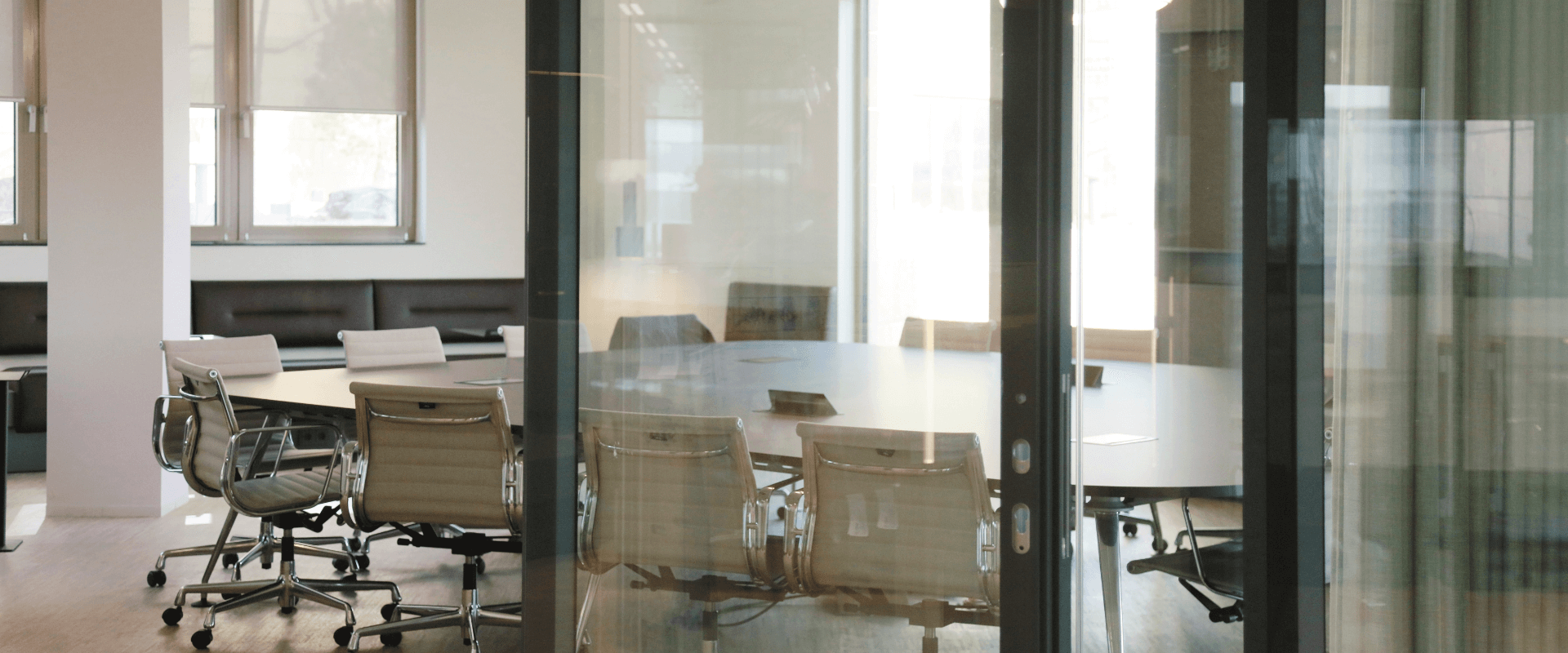 Moderne vergaderruimte met glazen wanden, ingebouwde verlichting en ergonomische stoelen.