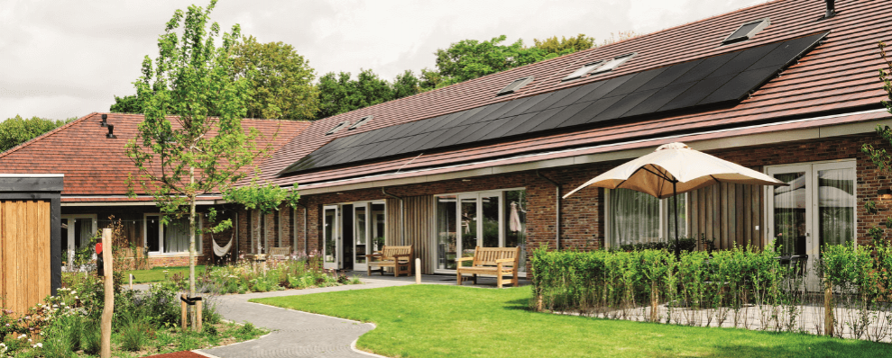 Het Jeroen Pit Huis in Amsterdam, een duurzaam zorggebouw met een groene tuin, zonnepanelen op het dak en een huiselijke uitstraling.