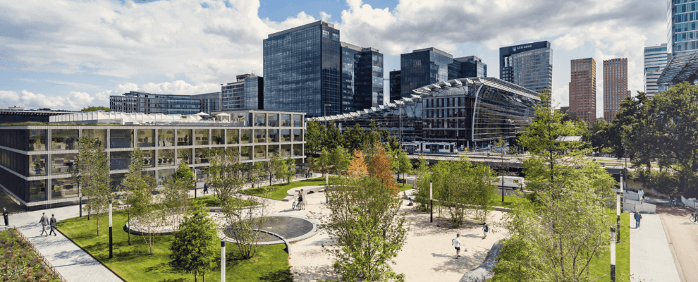 Het Strawinskyhuis in Amsterdam, een modern en duurzaam kantoorgebouw aan de Zuidas, omringd door groen en met een levendige stadsskyline op de achtergrond.