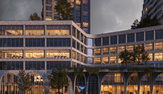 Avondzicht op The Ensemble, twee moderne torens met een uniek design en duurzaam karakter in een stedelijke omgeving.