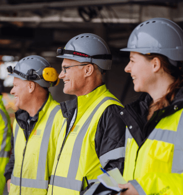 Een groep enthousiaste Bosman-medewerkers op een bouwlocatie, gekleed in veiligheidskleding en helmen. Ontdek het werken bij Bosman en word onderdeel van een hecht en innovatief team.