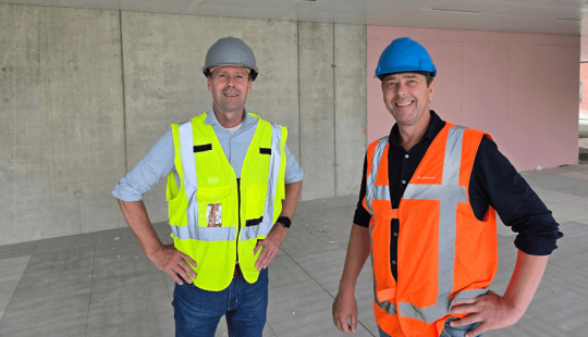 Twee medewerkers van Bosman en Hoogendoorn in bouwkleding en veiligheidshelmen op de bouwplaats,