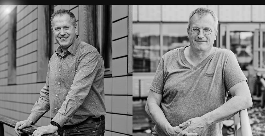 Twee Bosman-medewerkers poseren buiten voor een bedrijfsgebouw. Links een man in overhemd die vriendelijk lacht naar de camera, rechts een man in T-shirt met bril die ontspannen leunt tegen een railing.